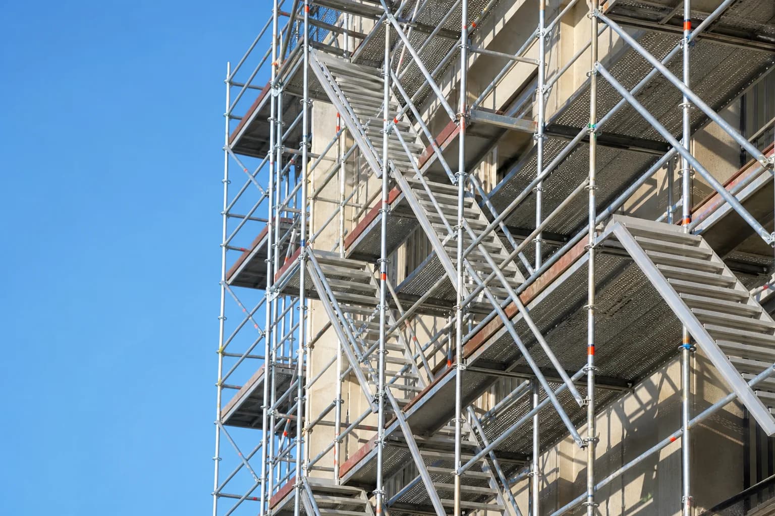 Scaffolding access staircase and platforms rising up the side of a building