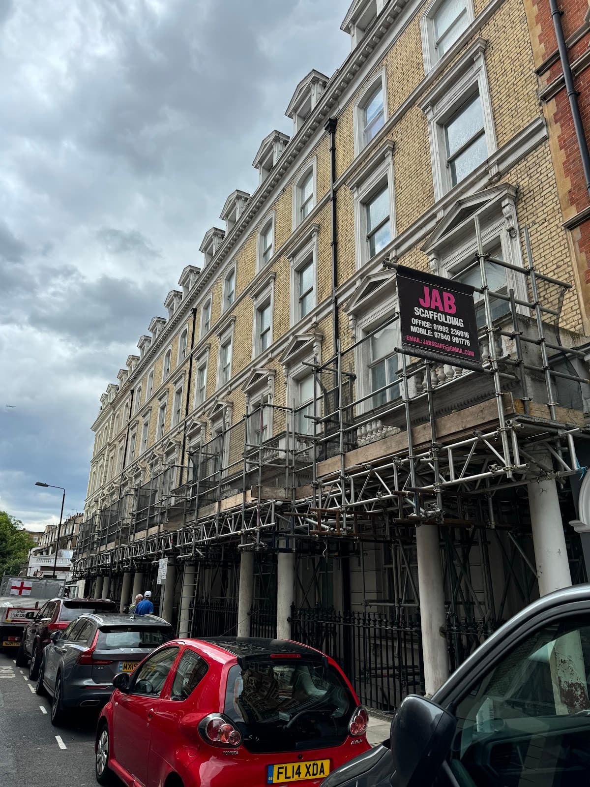 Scaffolding on a residential building with work vehicles on site